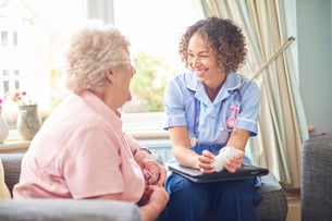 Smiling nurse visits a patient at home during a medication review