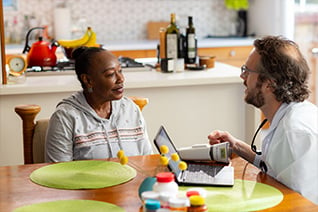 Signify Health clinician has conversation with health plan member at kitchen table