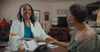 Signify Health clinician smiling while sitting with health plan member at table