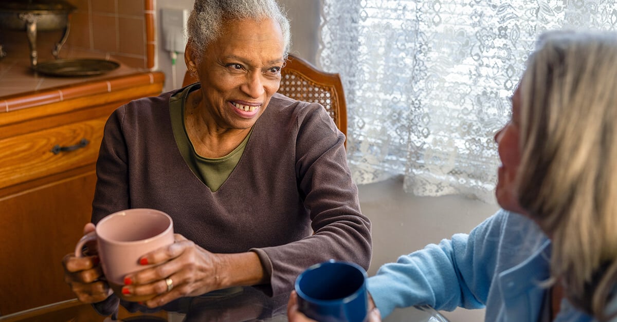 Member at home having coffee with friend at table.
