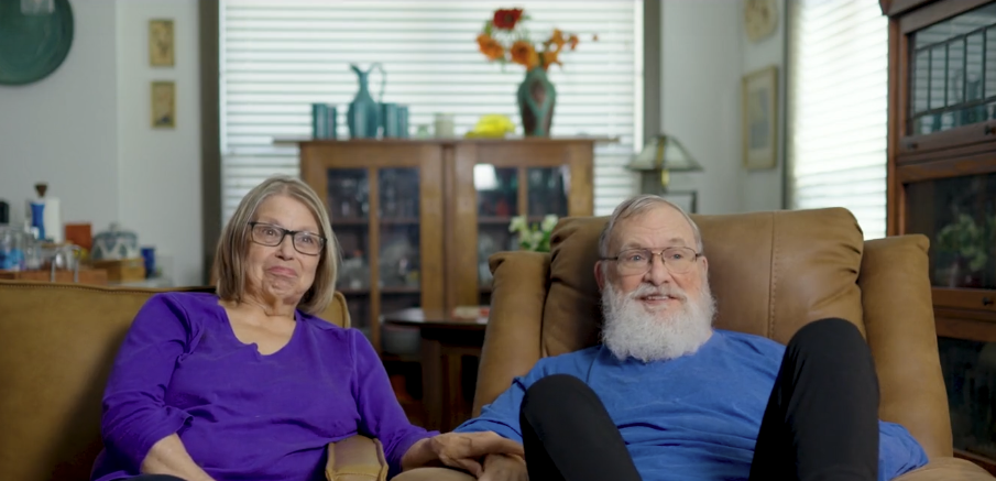 Carol and John in their home on couch