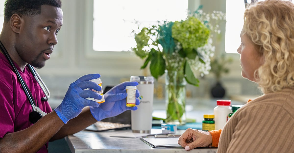 Clinician reviewing medication with member at home table.