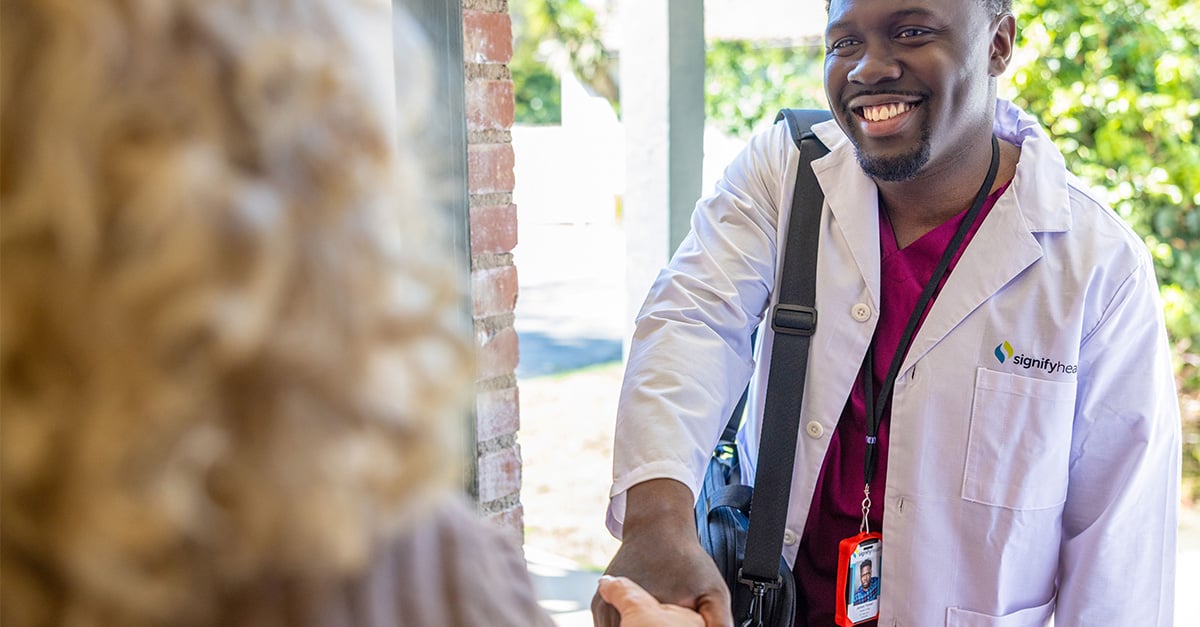 Physician assistant shaking hands with member at the front door before In-Home Health Evaluation
