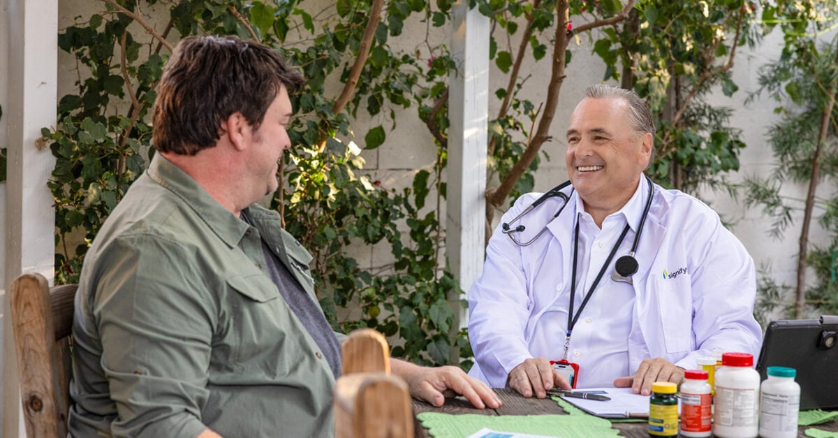 Clinician outside with member at home smiling. 