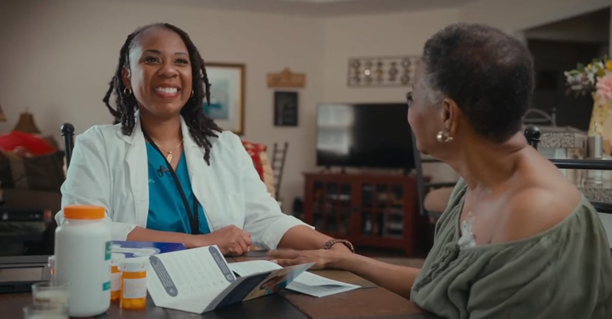 Signify Health clinician smiling while sitting with health plan member at table